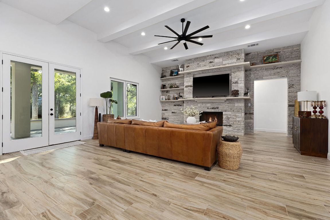 153 Fawn Hollow Elgin, TX 78621 - Photo 16 of 40 Living room with french doors, beam ceiling, light wood-style flooring, a stone fireplace, and recessed lighting