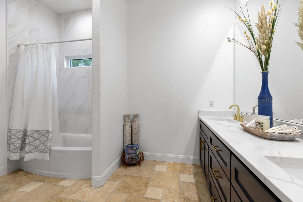 153 Fawn Hollow Elgin, TX 78621 - Photo 31 of 40 Bathroom with shower / bath combo with shower curtain, double vanity, and light stone finish floors