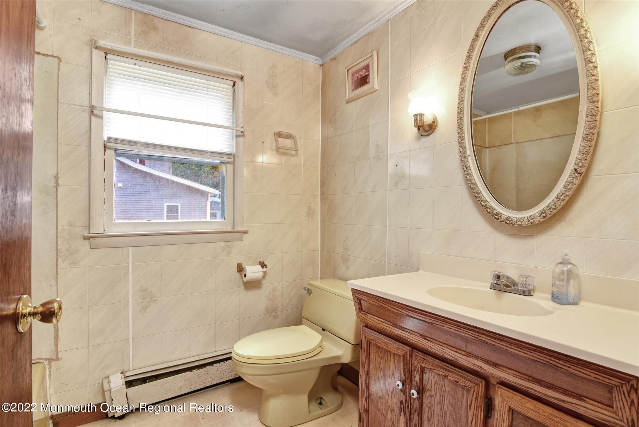 1350 Toms River Road Jackson, NJ 08527 - Photo 7 of 20 a bathroom with a sink a mirror a toilet and a window