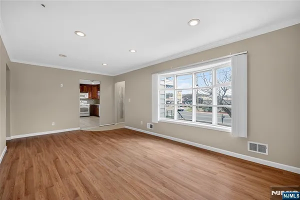 a view of an empty room with a window and wooden floor