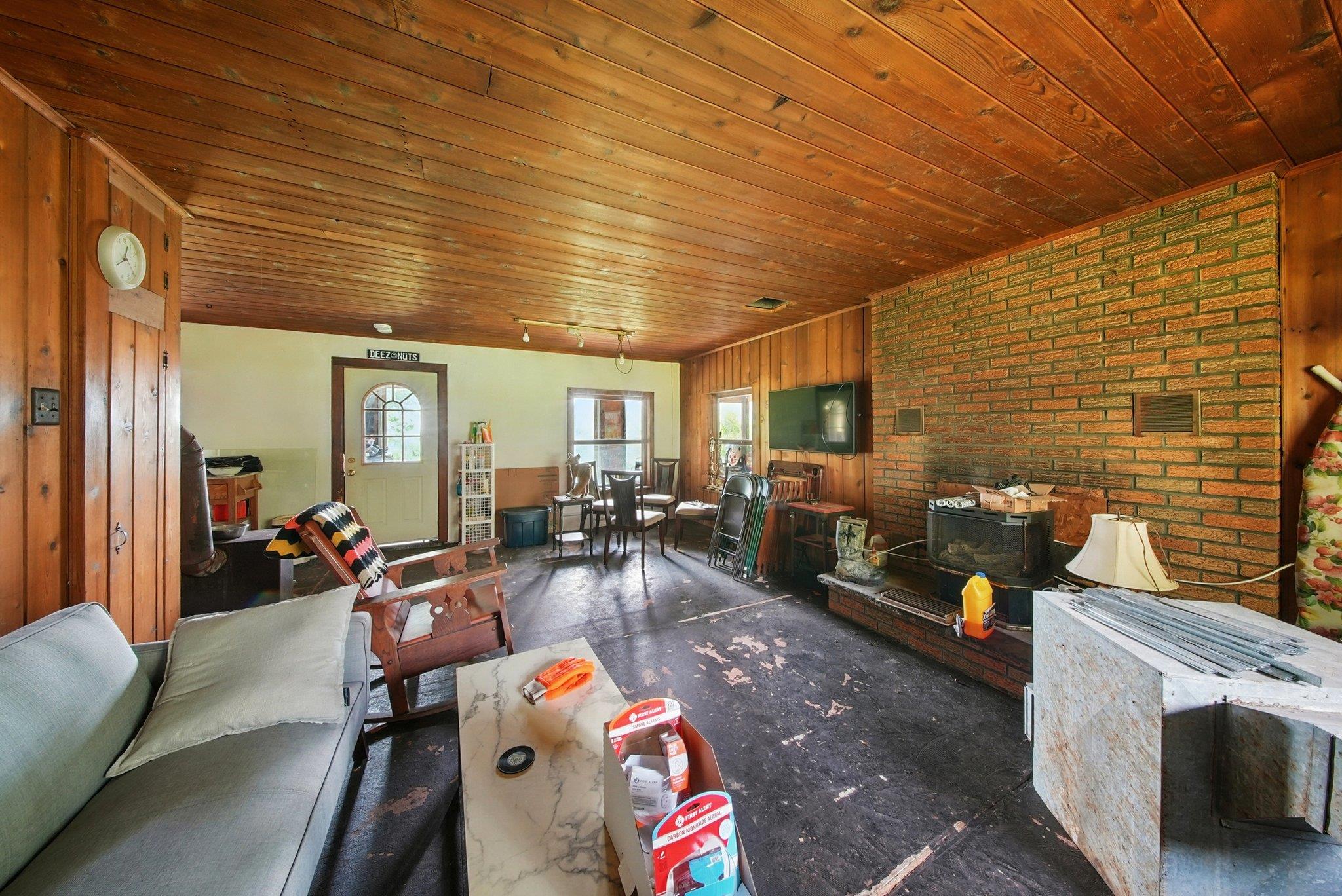 251 Haring Road Barryville, NY 12719 - Photo 5 of 30 Carpeted living room featuring wooden ceiling, brick wall, a wood stove, and wooden walls
