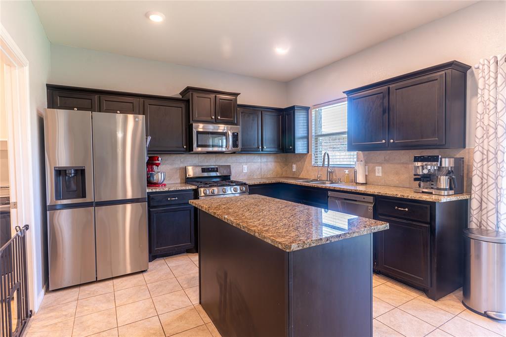 753 Rutherford Drive Crowley, TX 76036 - Photo 8 of 26 Kitchen featuring a central island, dark wood cabinetry, and stainless steel appliances