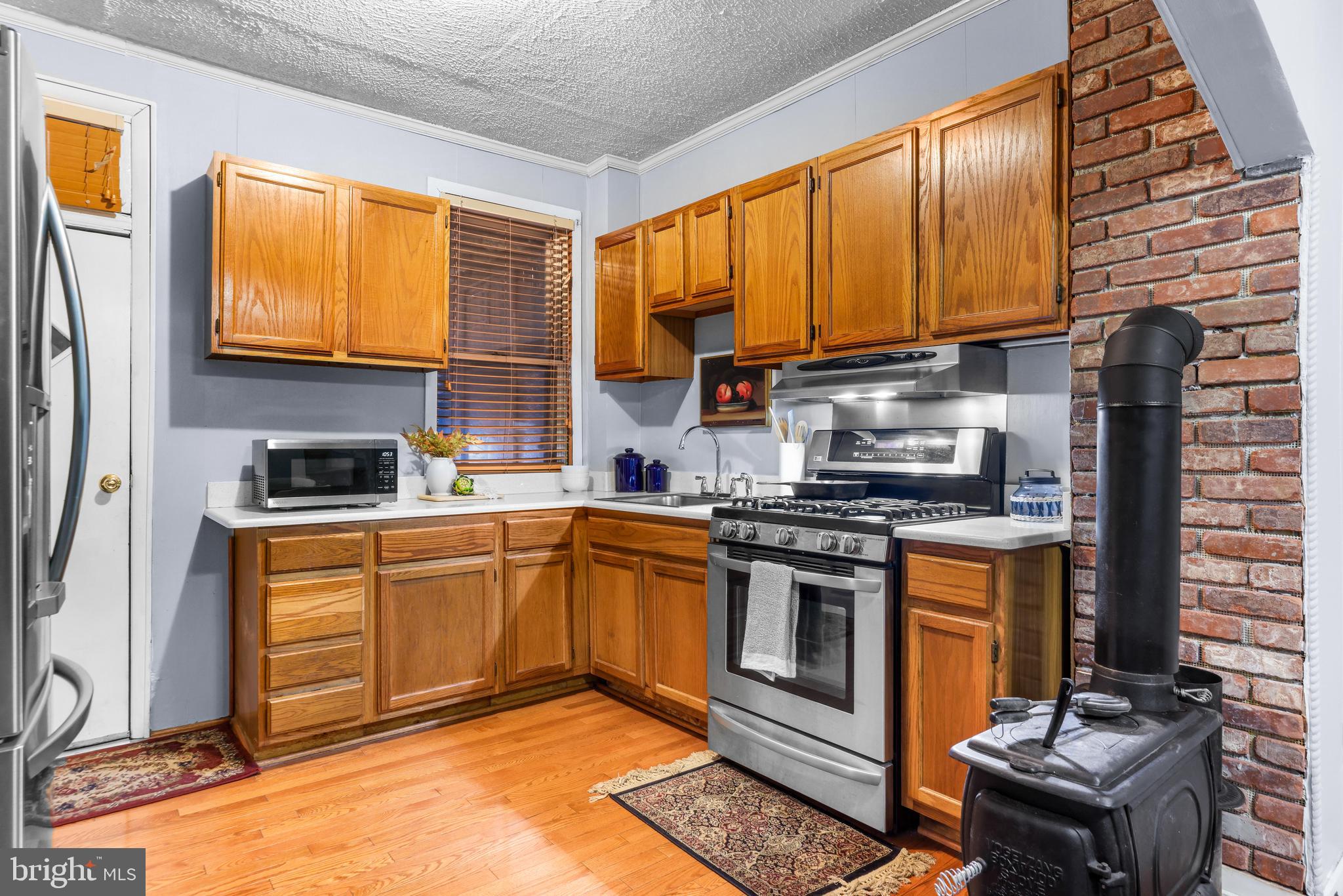 1113 South Robinson Street Baltimore, MD 21224 - Photo 11 of 38 a kitchen with stainless steel appliances granite countertop a stove top oven a sink dishwasher and cabinets with wooden floor