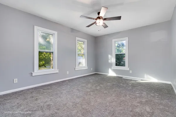 a view of an empty room with chandelier fan and fire place