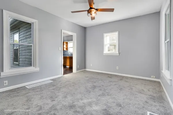an empty room with windows and fan