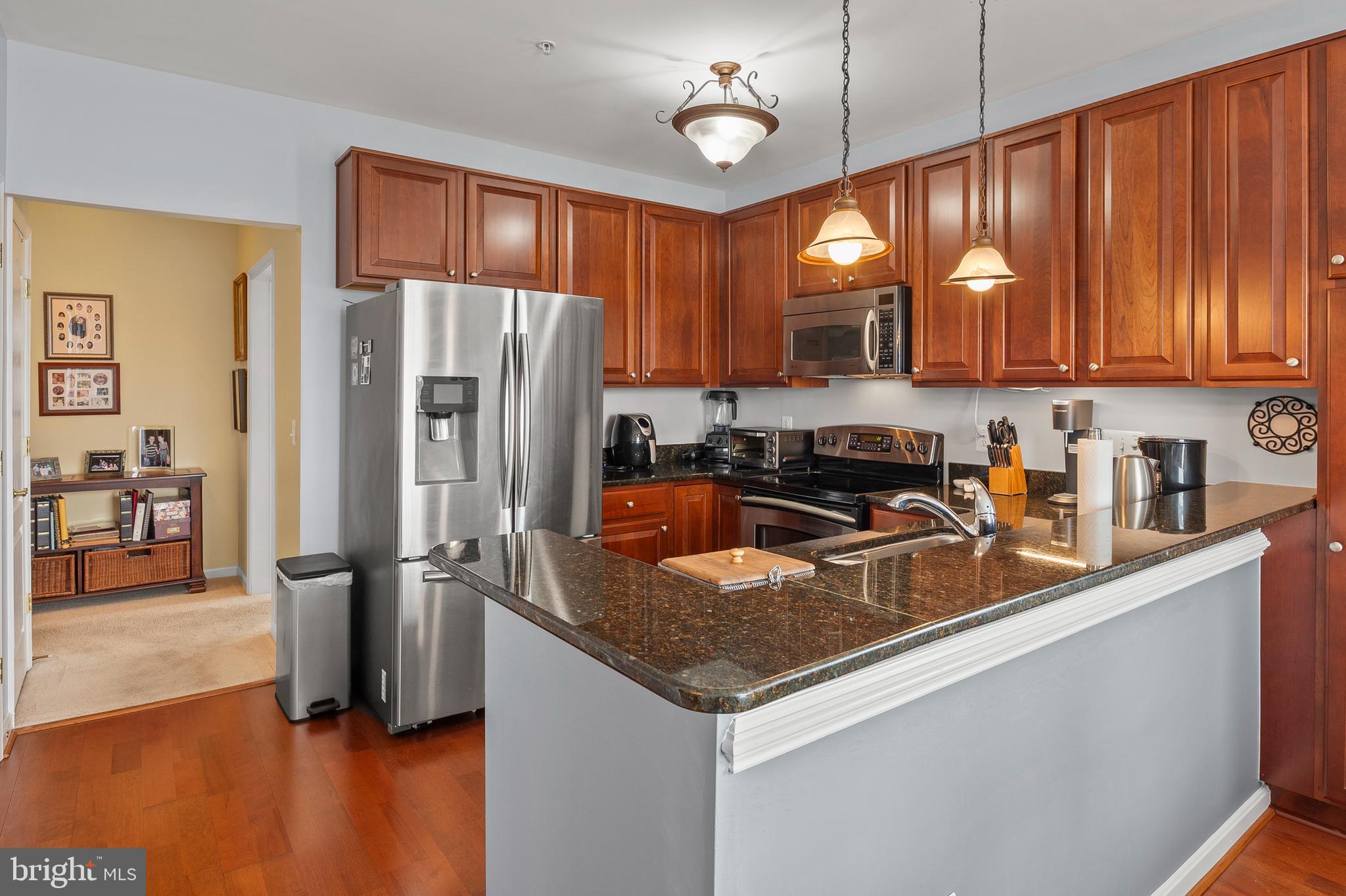 7305 Maplecrest Road, Unit 402 Elkridge, MD 21075 - Photo 13 of 55 a kitchen with stainless steel appliances granite countertop a refrigerator a sink dishwasher a stove and a refrigerator with wooden floor