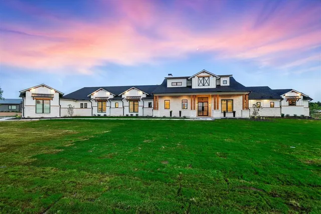 a view of a white house with a big yard and large trees