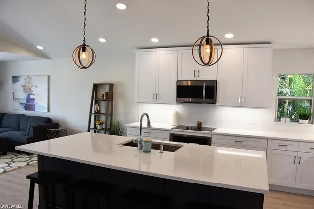 a kitchen with stainless steel appliances a table a sink and cabinets