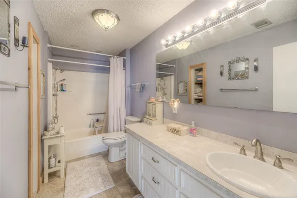 a spacious bathroom with a double vanity sink toilet mirror and bathtub