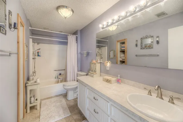 a spacious bathroom with a double vanity sink toilet mirror and bathtub