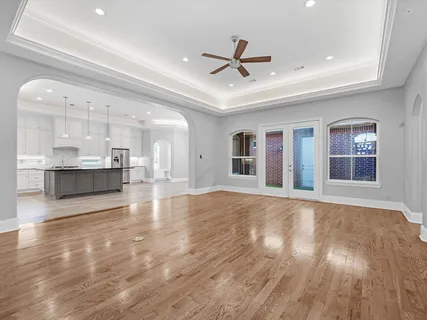 a view of an empty room with wooden floor and a ceiling fan