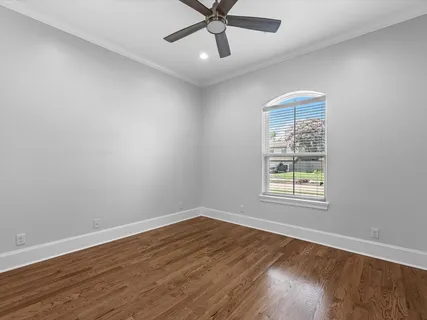 an empty room with wooden floor fan and windows
