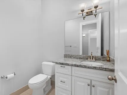 a bathroom with a granite countertop sink vanity mirror and toilet