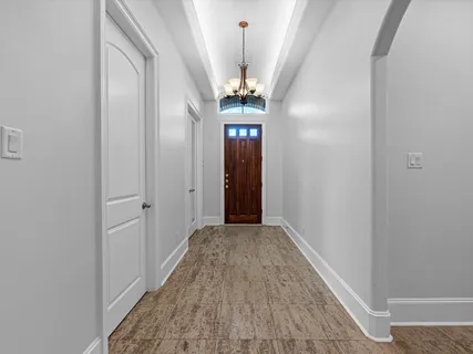 a view of a hallway with wooden floor and chandelier