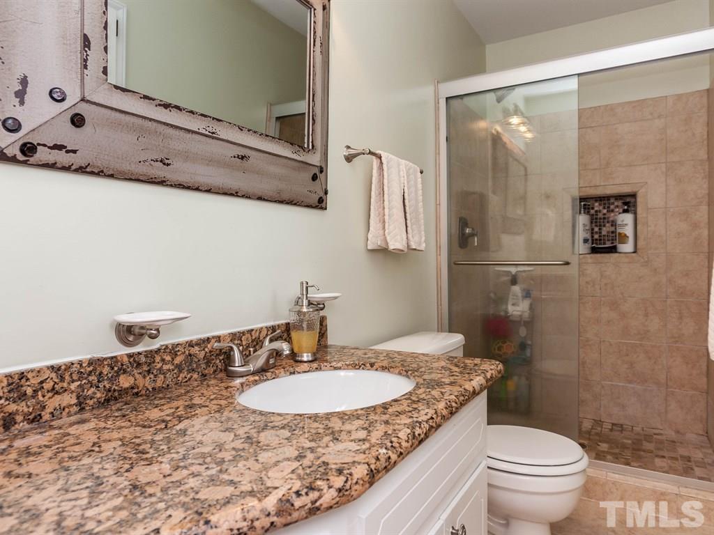 413 Crescent Court Raleigh, NC 27609 - Photo 17 of 25 a bathroom with a granite countertop sink a toilet a mirror and shower