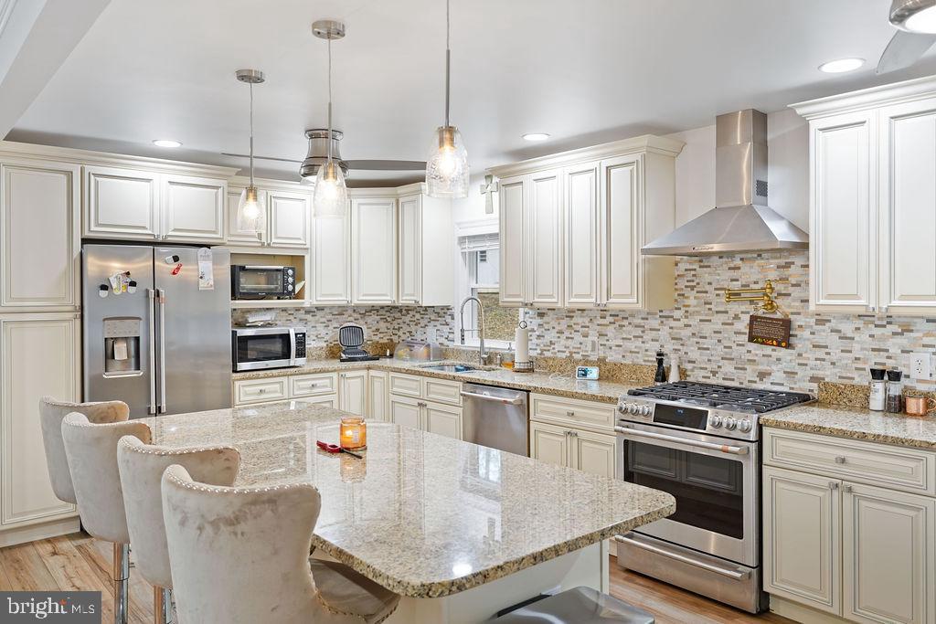 997 Mt Zion Marlboro Road Lothian, MD 20711 - Photo 20 of 58 a kitchen with stainless steel appliances granite countertop a stove a sink a refrigerator white cabinets and couches with wooden floor