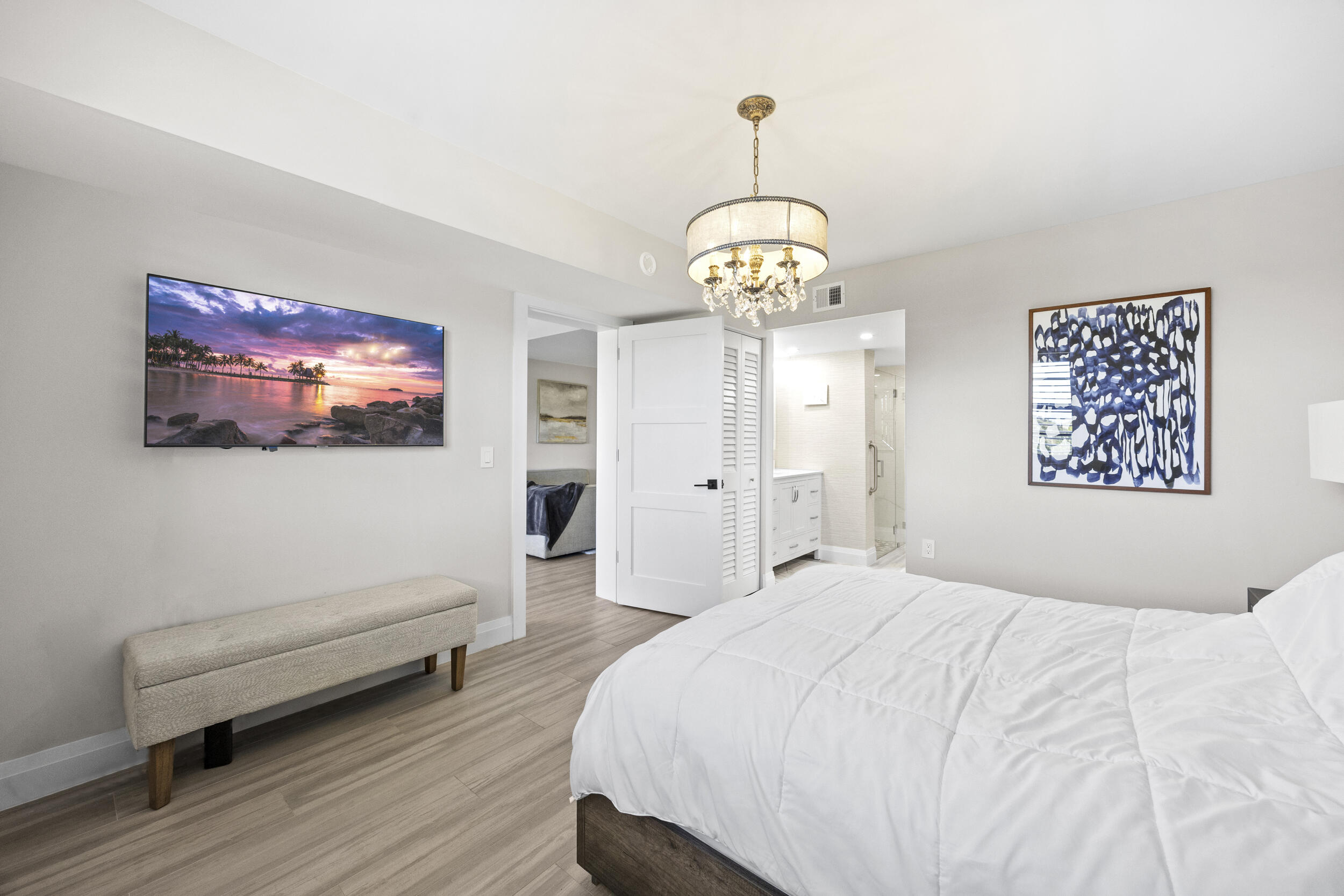 6061 Balboa Circle, Unit 403 Boca Raton, FL 33433 - Photo 23 of 44 a spacious bedroom with a bed and a chandelier