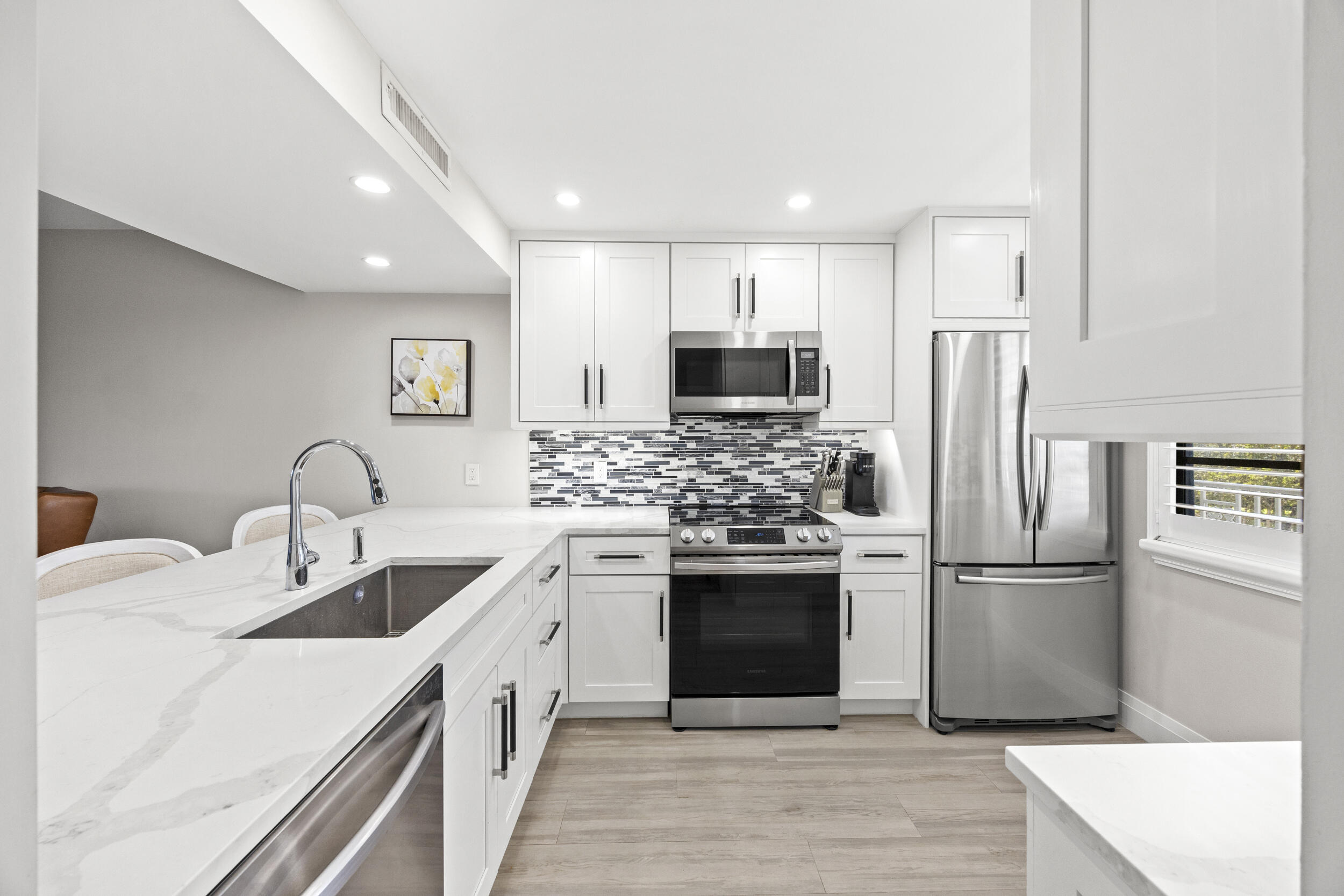 6061 Balboa Circle, Unit 403 Boca Raton, FL 33433 - Photo 7 of 44 a kitchen with kitchen island stainless steel appliances a refrigerator sink and microwave