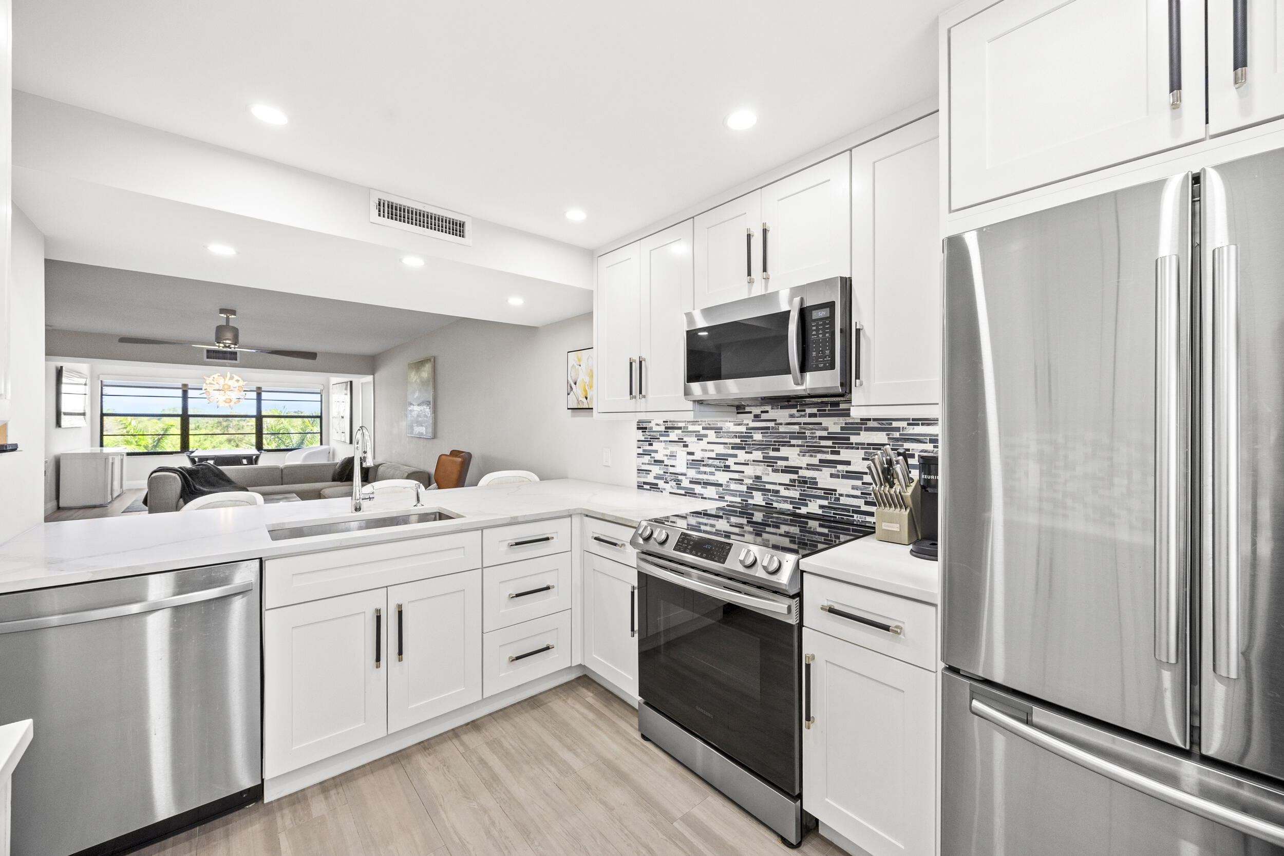 6061 Balboa Circle, Unit 403 Boca Raton, FL 33433 - Photo 9 of 44 a kitchen with white cabinets and stainless steel appliances