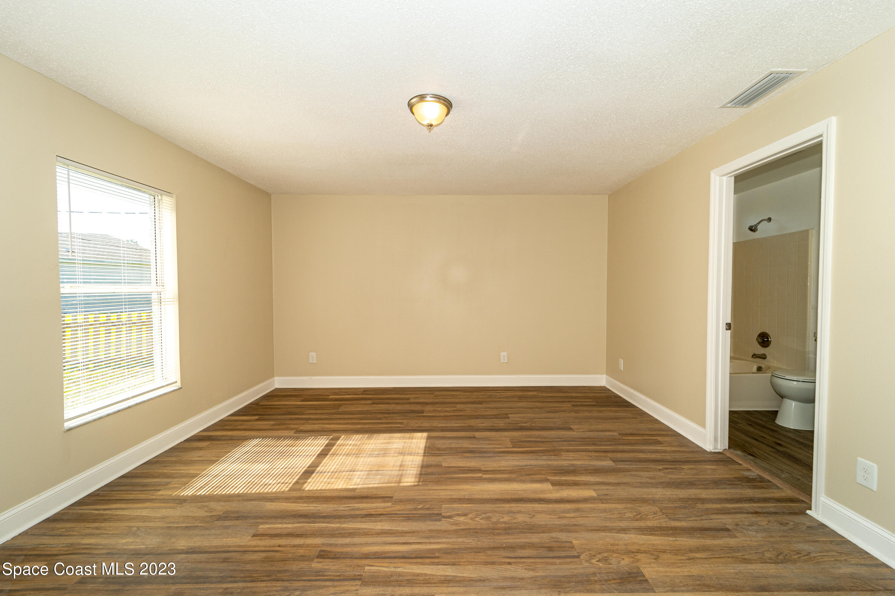 215 Trilby Road Southwest Palm Bay, FL 32908 - Photo 11 of 19 a view of an empty room with wooden floor and a window