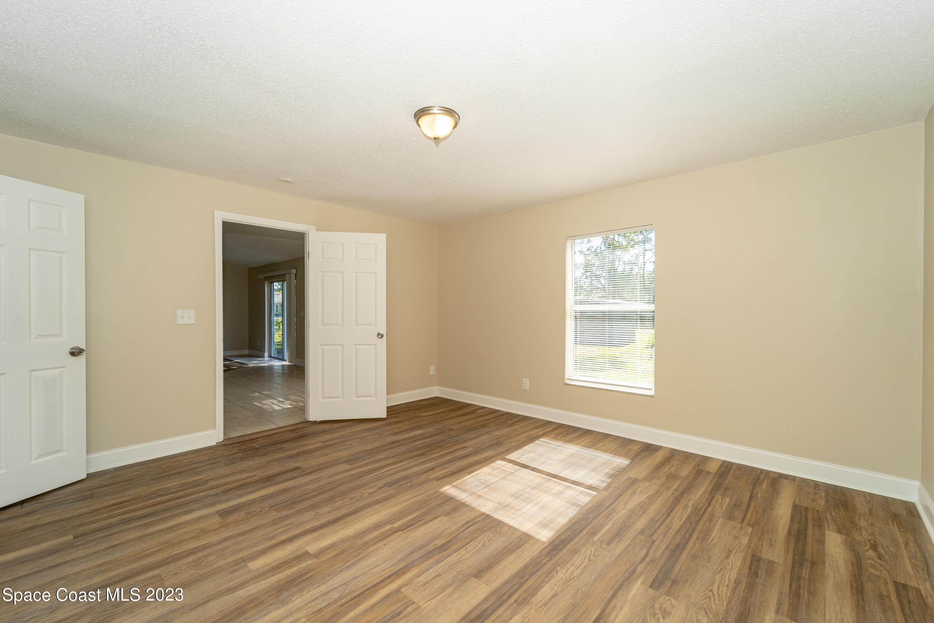 215 Trilby Road Southwest Palm Bay, FL 32908 - Photo 14 of 19 a view of an empty room with wooden floor and a window