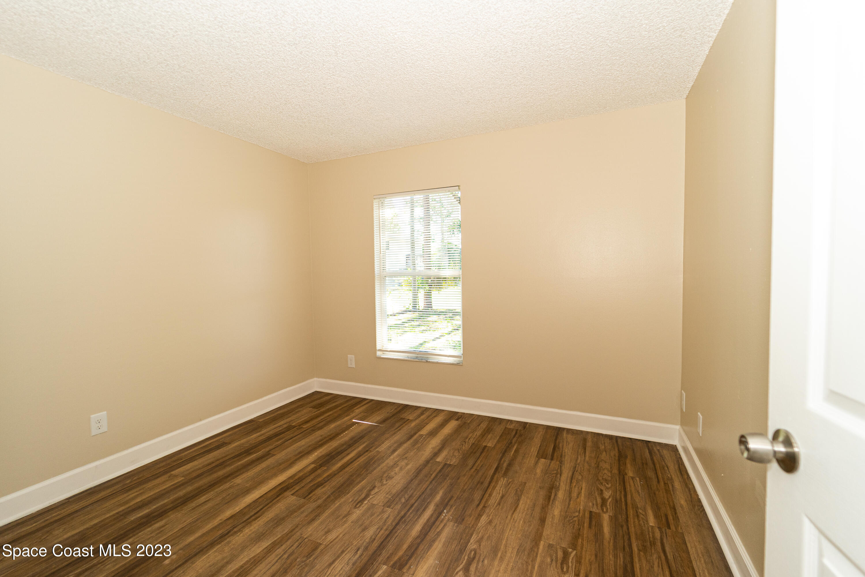 215 Trilby Road Southwest Palm Bay, FL 32908 - Photo 7 of 19 an empty room with wooden floor and windows