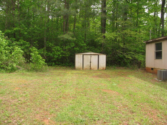 599 Rocky Creek Road Forsyth, GA 31029 - Photo 2 of 9 a backyard of a house with plants and large trees