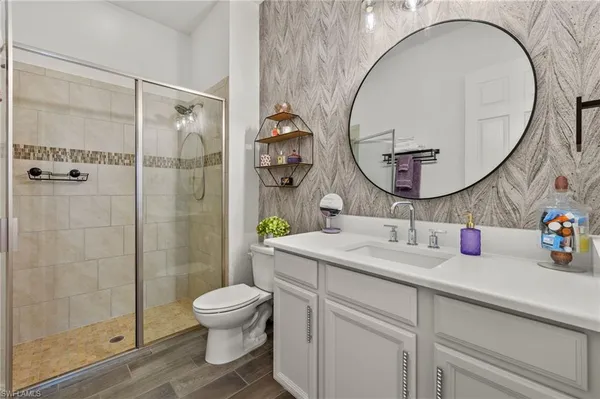 a bathroom with a toilet sink vanity granite and a mirror