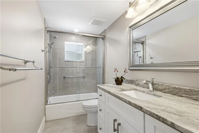 a bathroom with a granite countertop sink a toilet and shower
