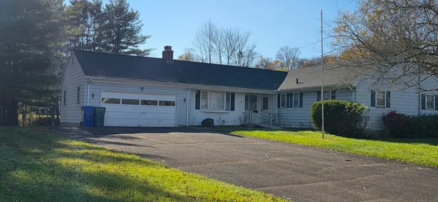 a view of house with yard and trees in the background