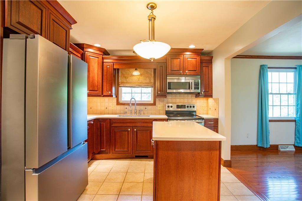 103 Mowry Road Monaca, PA 15061 - Photo 5 of 38 a kitchen with stainless steel appliances granite countertop a refrigerator a sink dishwasher a dining table and chairs with wooden floor