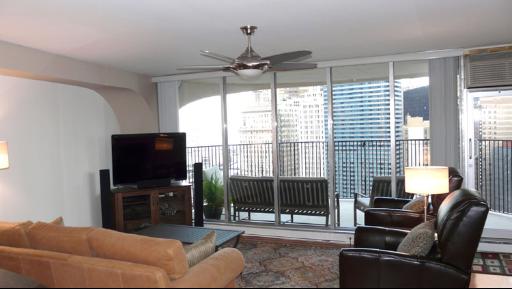 300 North State Street, Unit 2609 Chicago, IL 60654 - Photo 5 of 9 a living room with furniture a flat screen tv and a floor to ceiling window