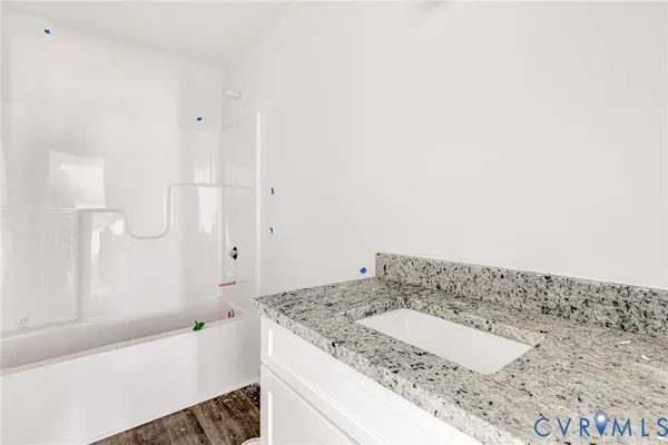 a bathroom with a granite countertop sink and a bathtub