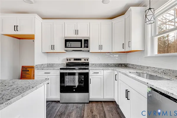 a kitchen with stainless steel appliances granite countertop a stove a sink and a microwave