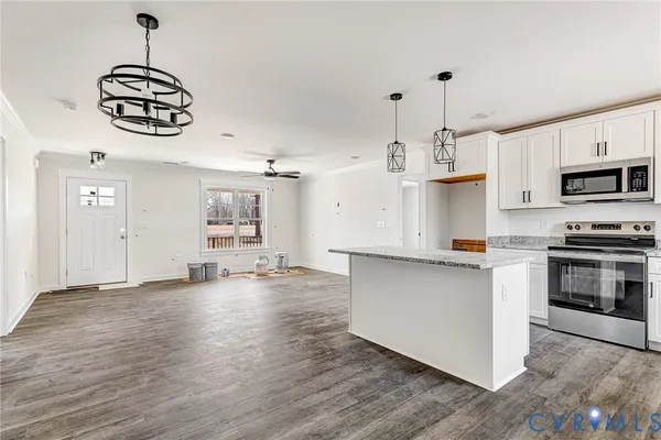 a kitchen with kitchen island granite countertop a stove top oven a sink a counter space and cabinets