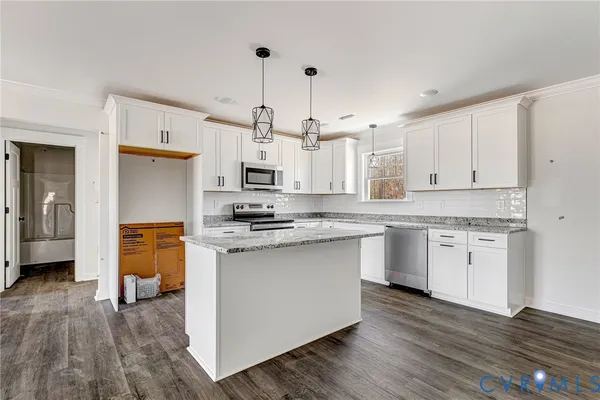 a kitchen with stainless steel appliances granite countertop a white stove top oven a sink dishwasher and a refrigerator with wooden floor