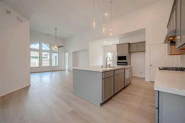 a large kitchen with a large counter top space a sink stainless steel appliances and cabinets