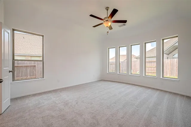 an empty room with windows and fan
