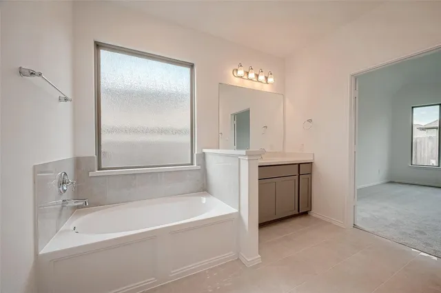 a spacious bathroom with a tub sink and a mirror