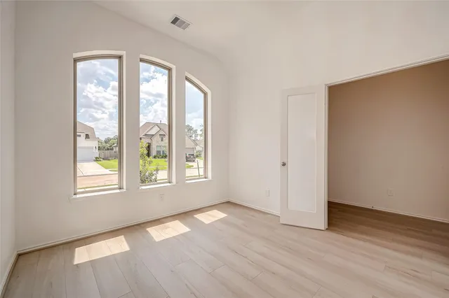 an empty room with wooden floor and windows
