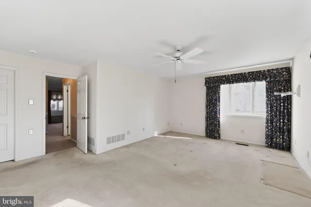 an empty room with closet and a ceiling fan