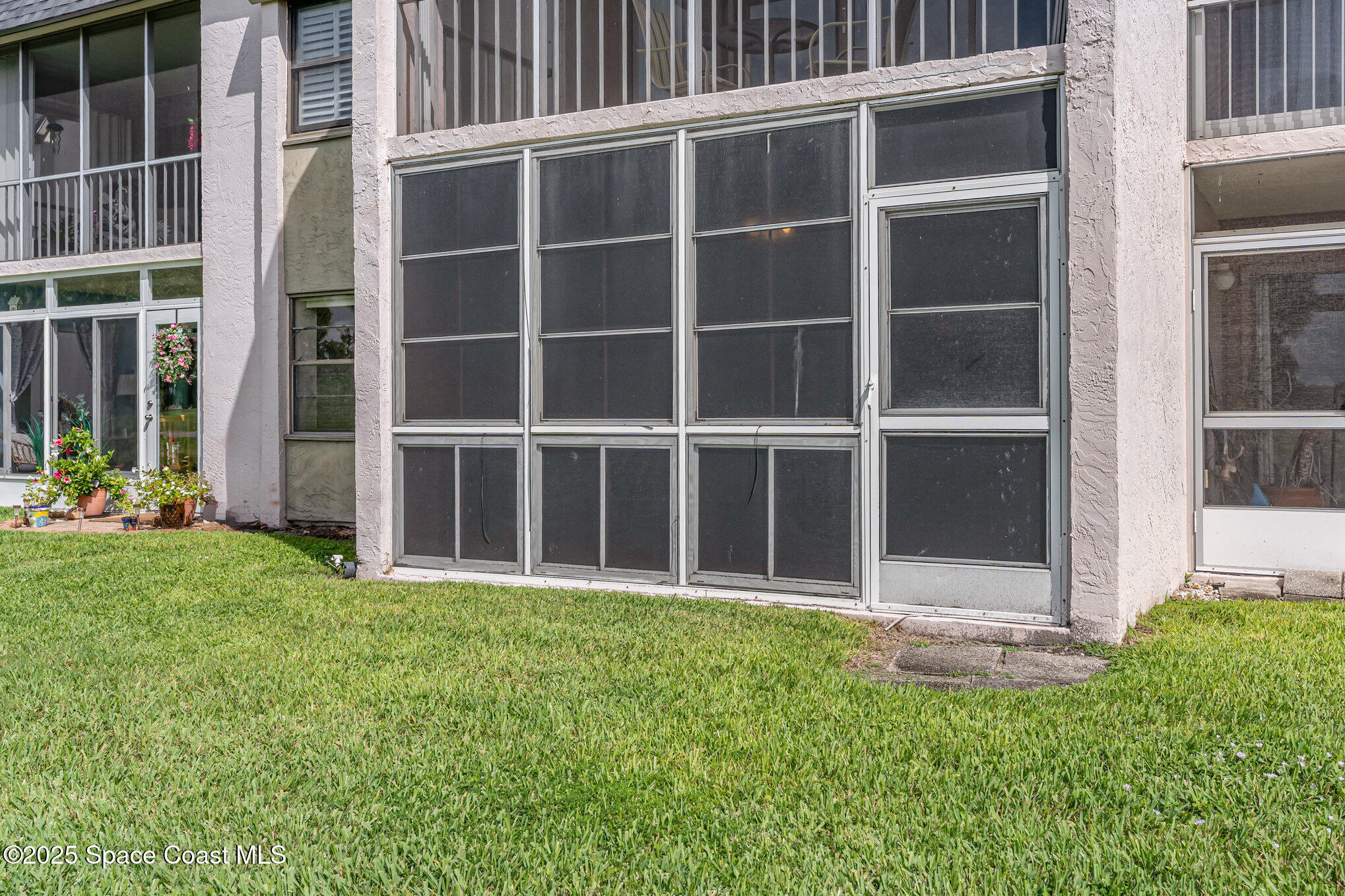 2727 North Wickham Road, Unit 10210 Melbourne, FL 32935 - Photo 24 of 35 a view of a backyard with potted plants and large window