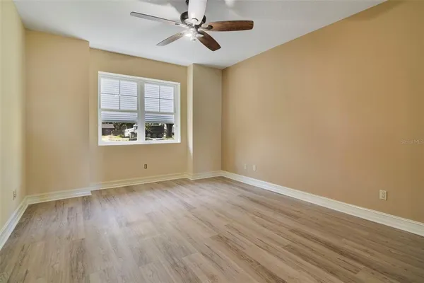 a view of an empty room with a window and wooden floor