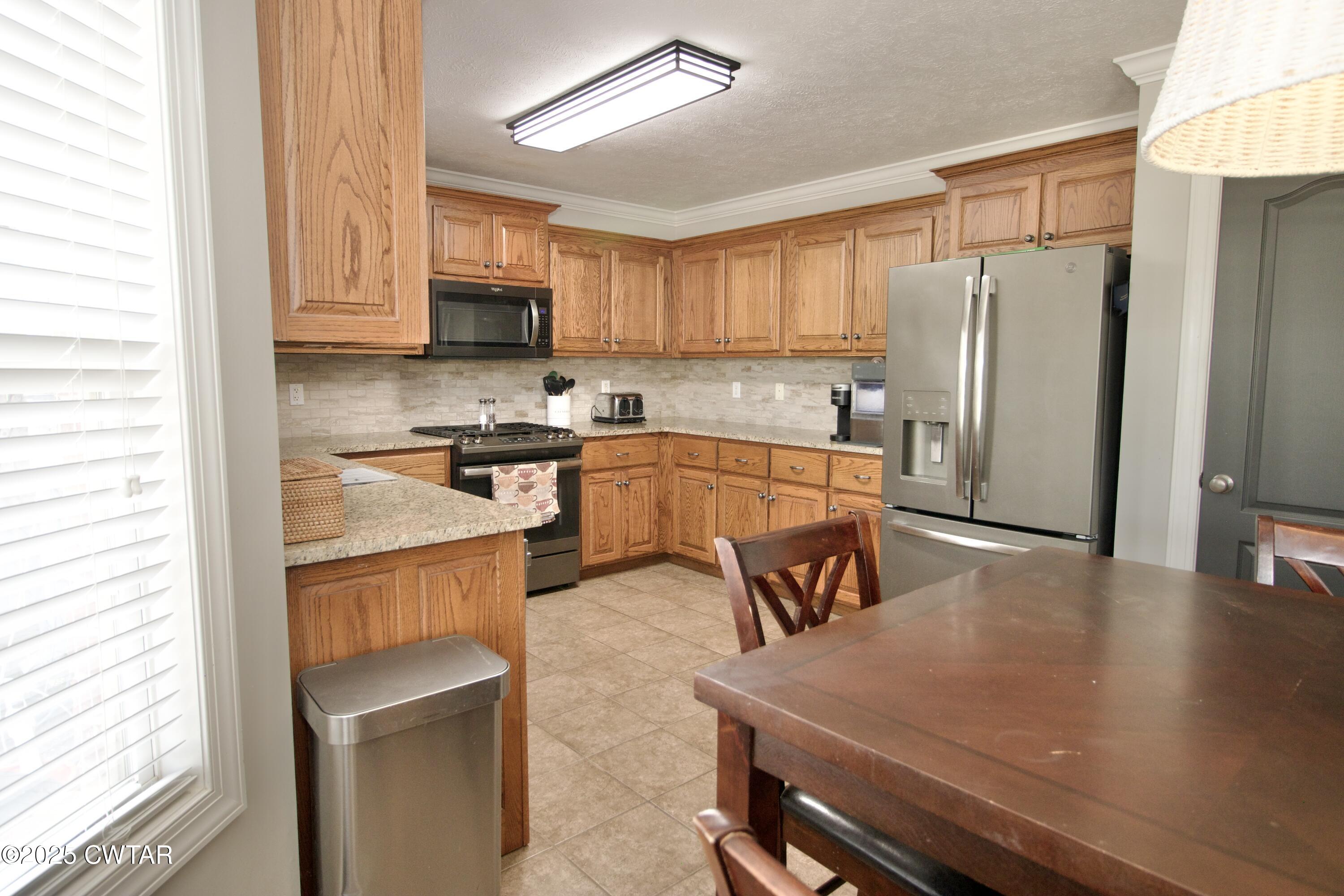 177 Fawn Ridge Lane Medina, TN 38355 - Photo 30 of 44 a kitchen with stainless steel appliances granite countertop a stove a refrigerator a sink a dining table and chairs with wooden floor