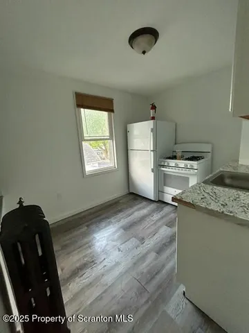 a kitchen with a stove a refrigerator and wooden floor