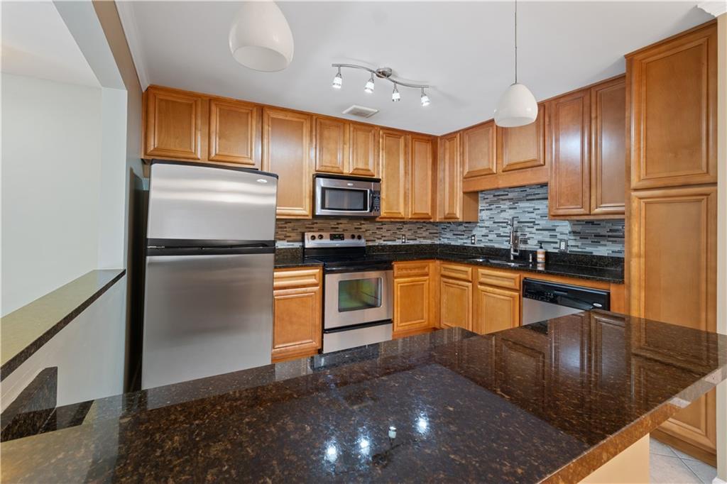 1468 Briarwood Road Northeast, Unit 1104 Atlanta, GA 30319 - Photo 6 of 15 a kitchen with stainless steel appliances granite countertop a refrigerator a stove a sink and a microwave