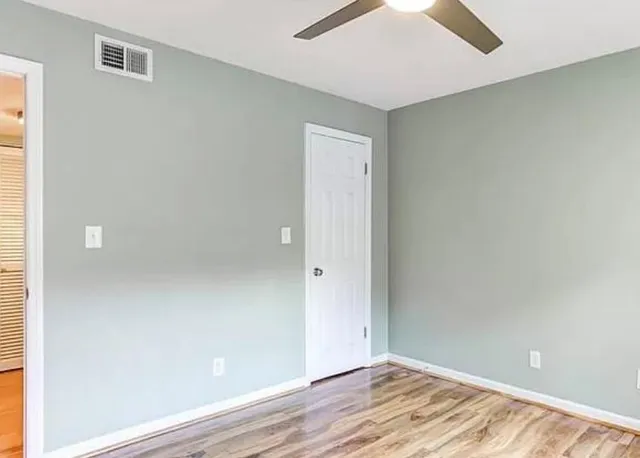 an empty room with wooden floor and fan