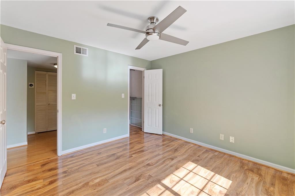1468 Briarwood Road Northeast, Unit 1104 Atlanta, GA 30319 - Photo 9 of 15 an empty room with wooden floor and a ceiling fan