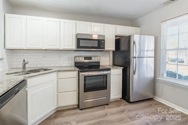 a kitchen with stainless steel appliances granite countertop a refrigerator stove a sink and a microwave