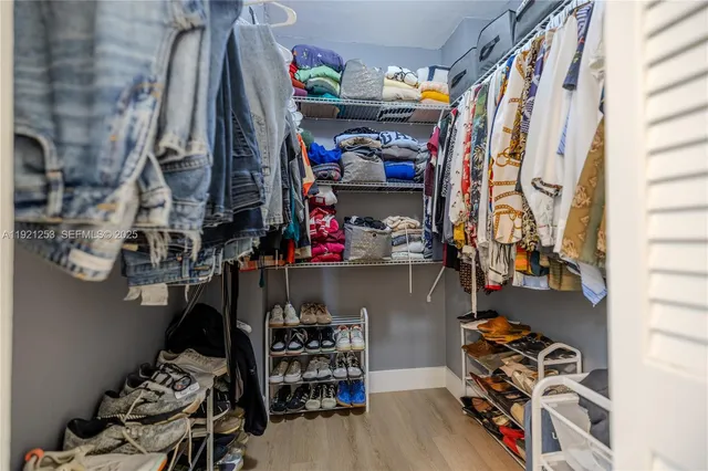 a view of walk in closet with clothes and shoes